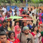 Chinese visitors celebrating Pohela Boishakh in Bangladesh during Mangal Shobhajatra with colorful cultural masks, traditional Bengali artwork, and festive New Year atmosphere — Bangladesh Guided Tours