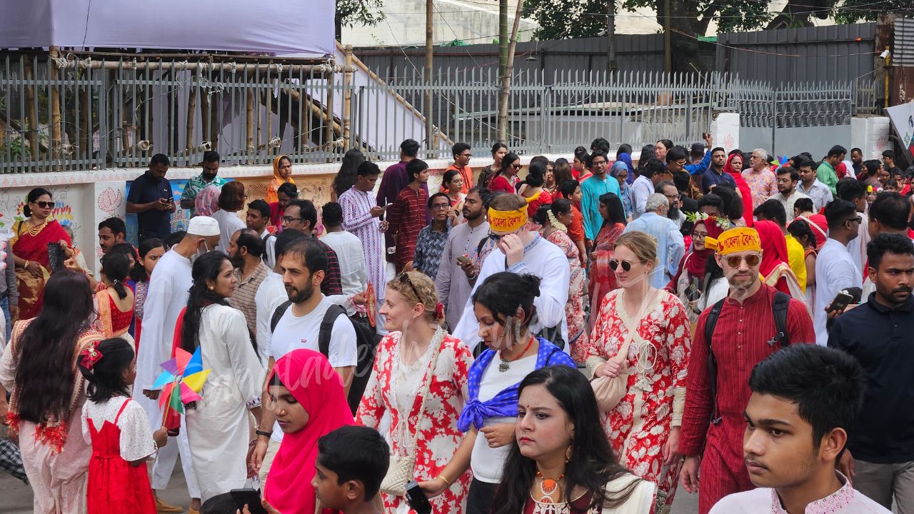 German tourists celebrating Pohela Boishakh in Bangladesh during the lively Mangal Shobhajatra with traditional masks, bright folk motifs, and New Year festivities — Bangladesh Guided Tours