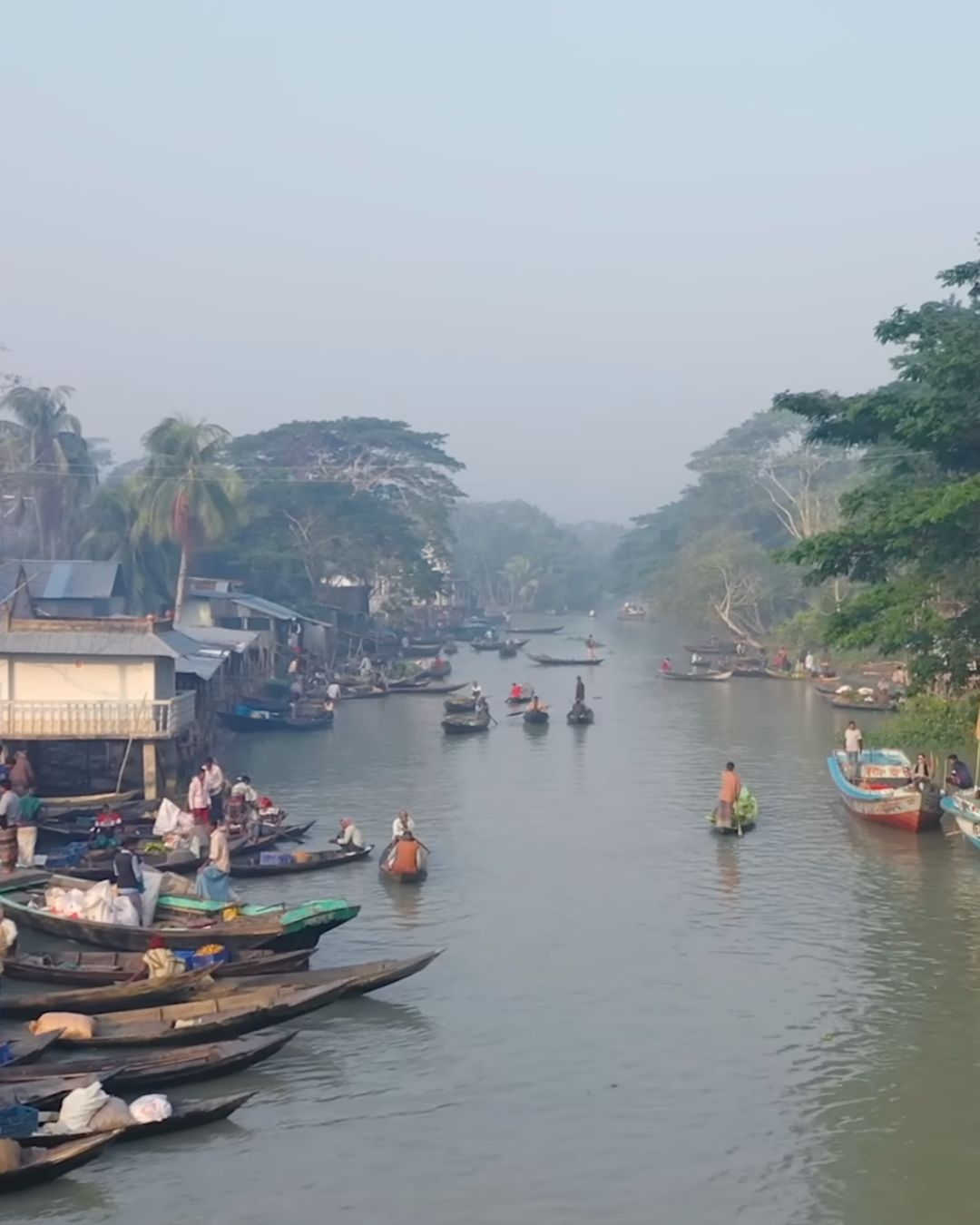 Local traders selling goods from wooden boats in floating market Bangladesh