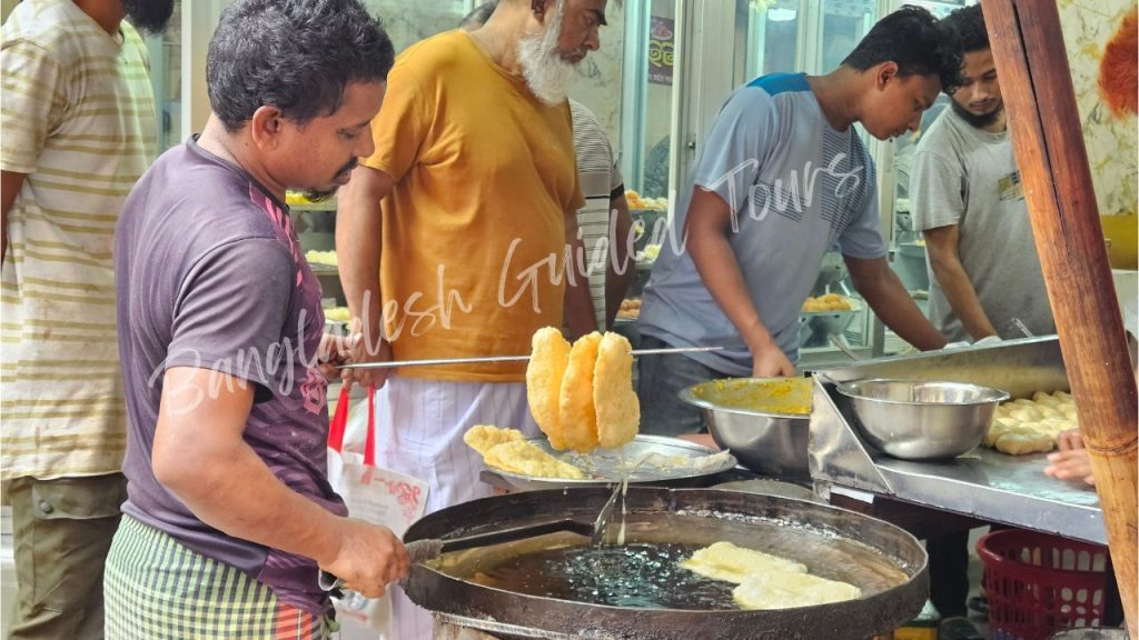 Freshly fried Boro Daler Puri served with spicy aloo bhaji in Old Dhaka, a traditional Bengali street food breakfast in Bangladesh