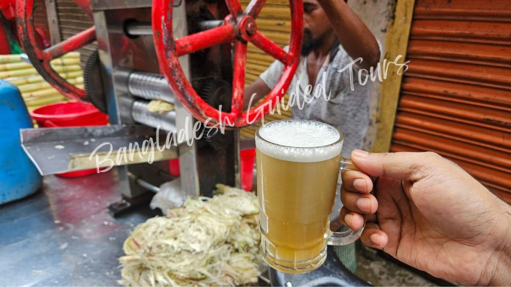 Fresh sugarcane juice being extracted from crushed sugarcane stalks at an Old Dhaka street stall, a natural sweet drink for foreign tourists in Bangladesh